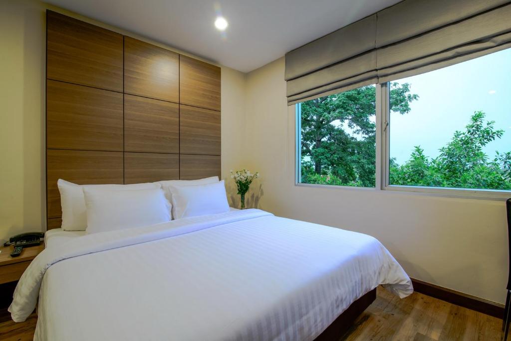 a bedroom with a large white bed and a window at Sima Thani Hotel in Nakhon Ratchasima