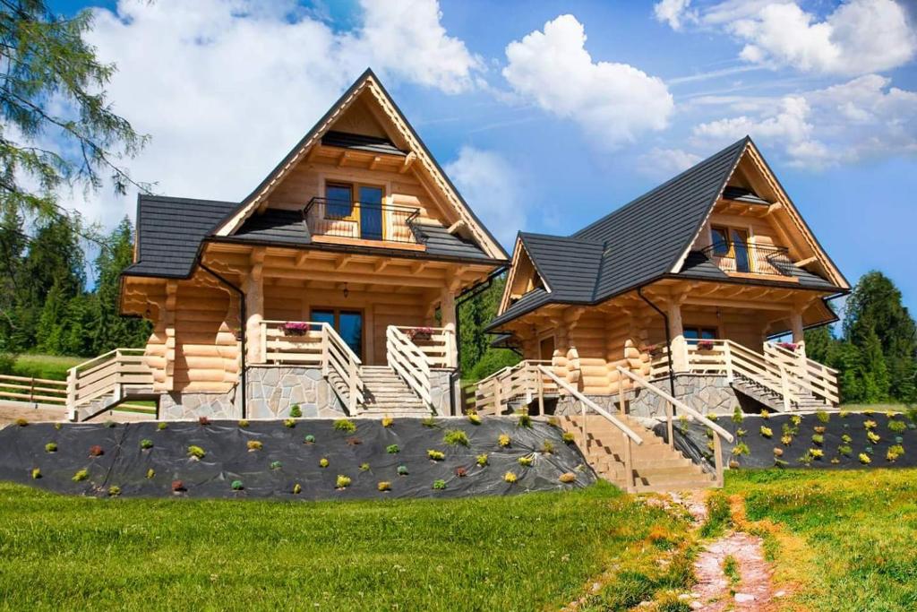 a log cabin with a porch and stairs in front of it at Domki pod lasem in Nowe Bystre
