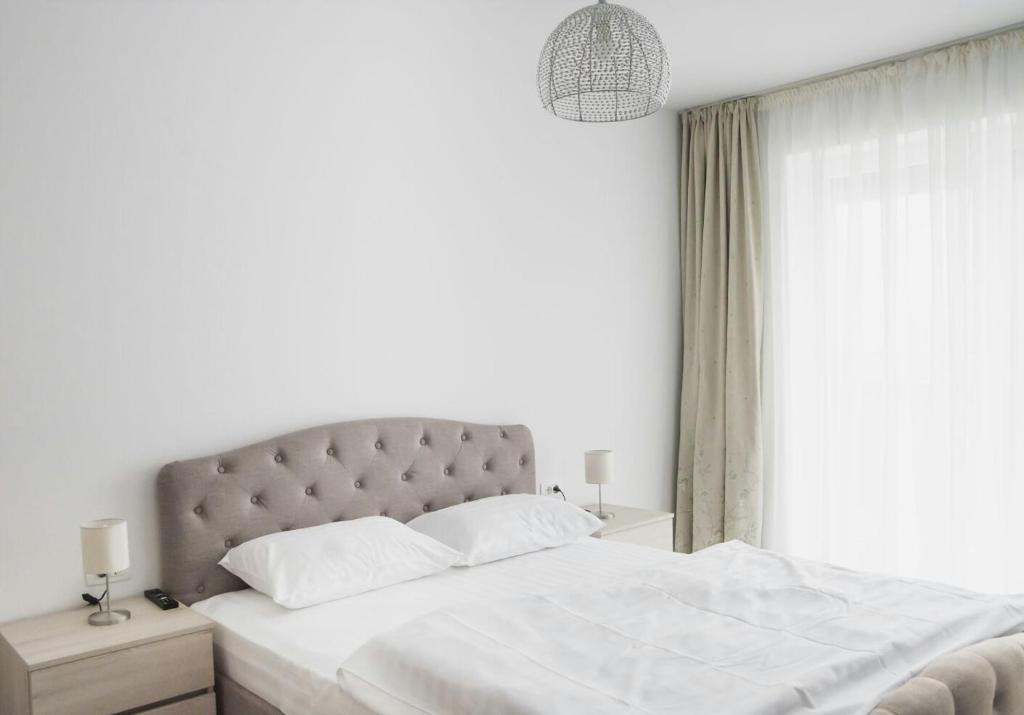 a white bedroom with a large bed and a window at Apartament 4Tourists in Braşov