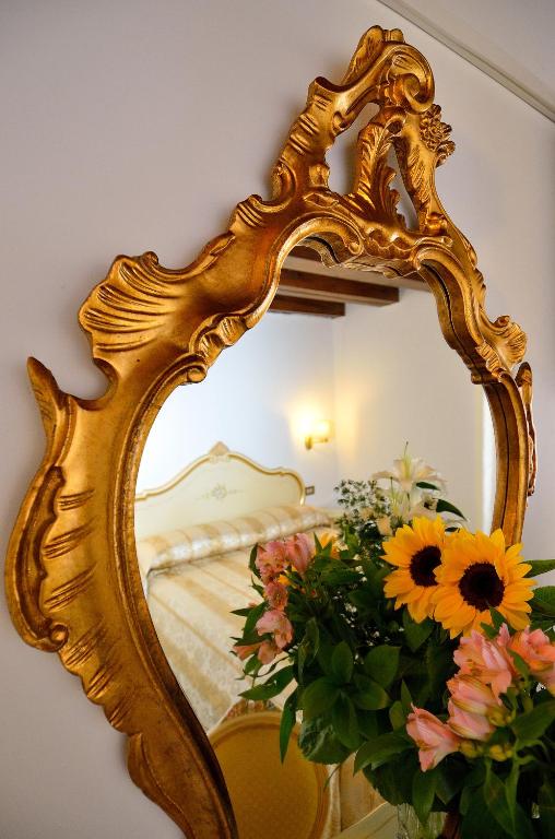 an ornate gold mirror with flowers in front of a bed at Hotel Orion in Venice