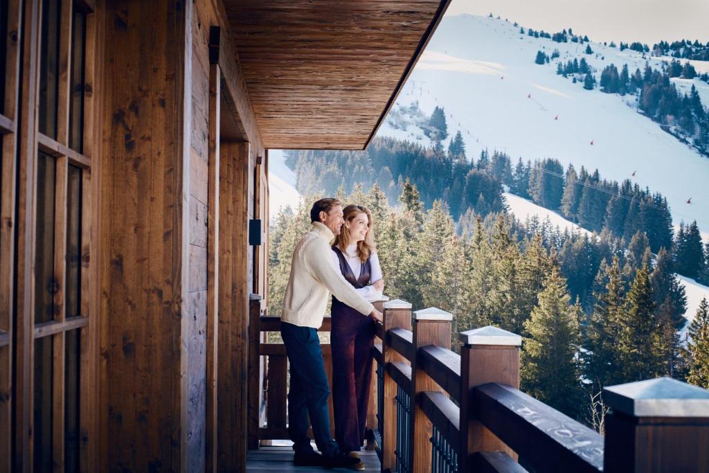 a man and woman standing on the balcony of a cabin at Apogée Courchevel, Oetker Hotels in Courchevel