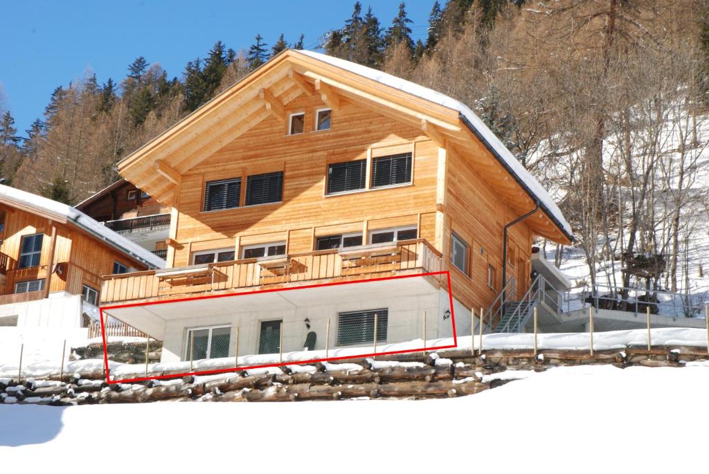 a building with a wooden roof on top of snow at Haus Melodie in Wiler
