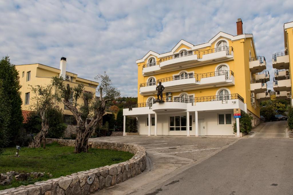 un bâtiment jaune avec des balcons sur son côté dans l'établissement Hotel Crnogorska Kuća, à Podgorica