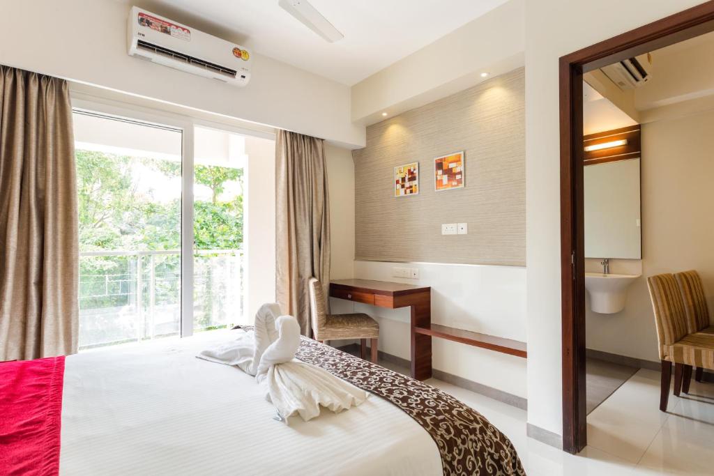 a bedroom with a bed and a window and a desk at D Homz Suites in Cochin