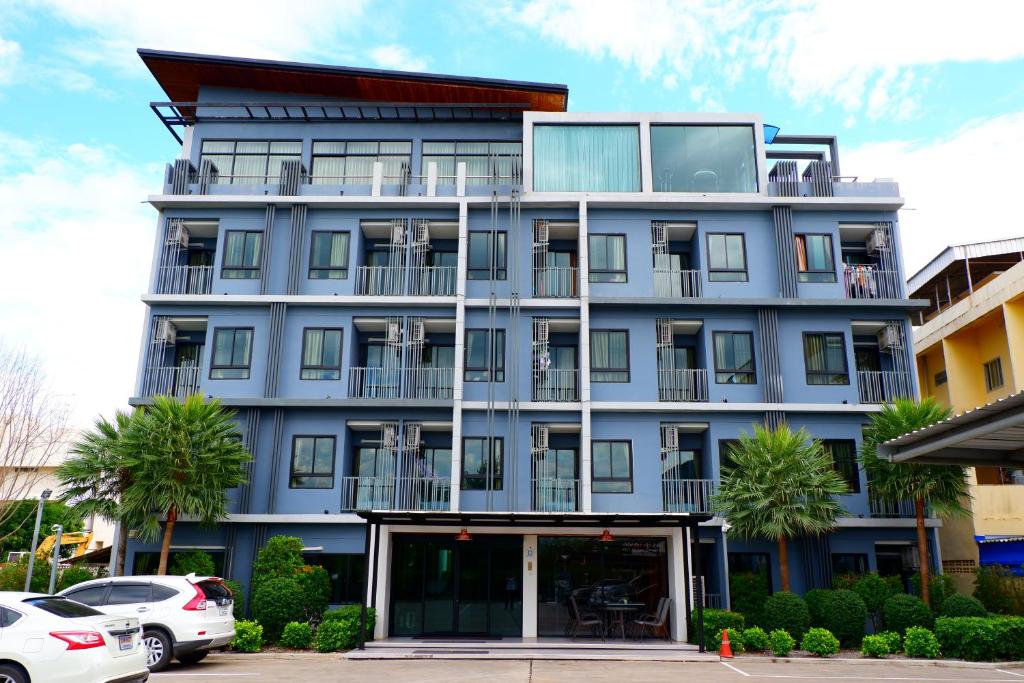 a tall blue building with cars parked in front of it at The D257 Hotel in Phetchabun