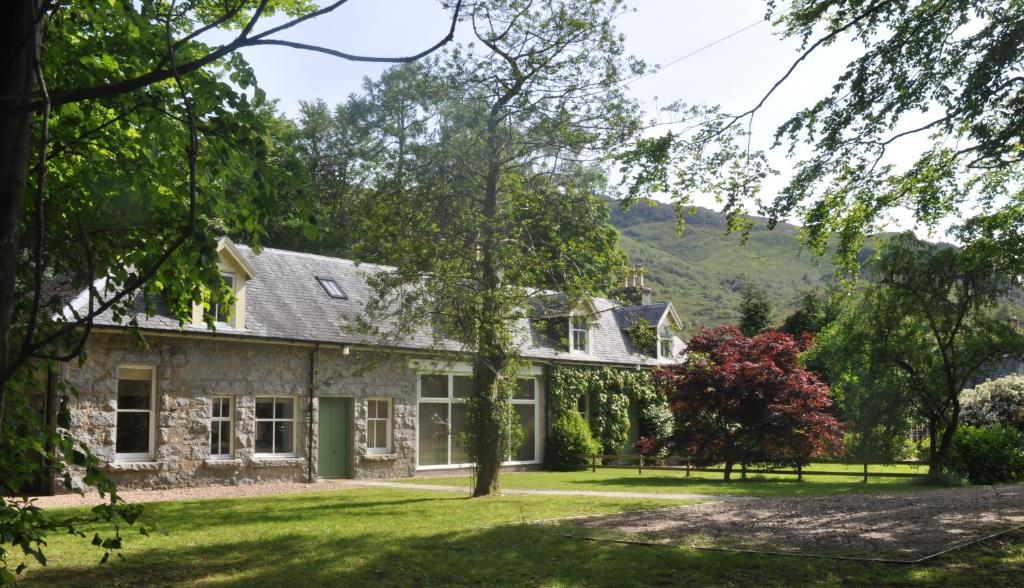 een uitzicht op een huis met een tuin bij The Old Coach House, Alltshellach Cottages in North Ballachulish
