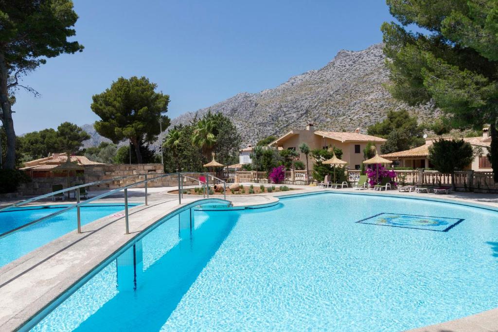 une piscine dans un complexe hôtelier avec une montagne en arrière-plan dans l'établissement Villa Gran Voramar Cala, à Pollença