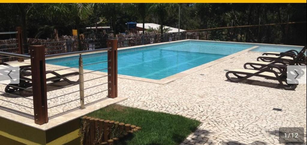 a swimming pool with chairs and a fence around it at Vila Verona in Praia do Forte