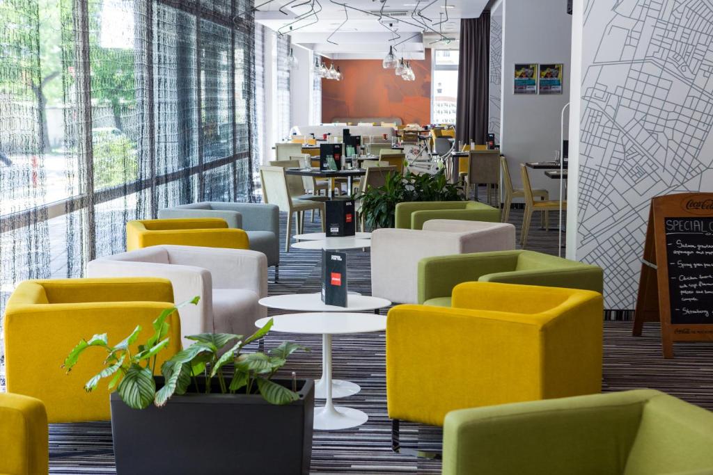 a restaurant with yellow and green chairs and tables at Park Inn By Radisson Budapest in Budapest