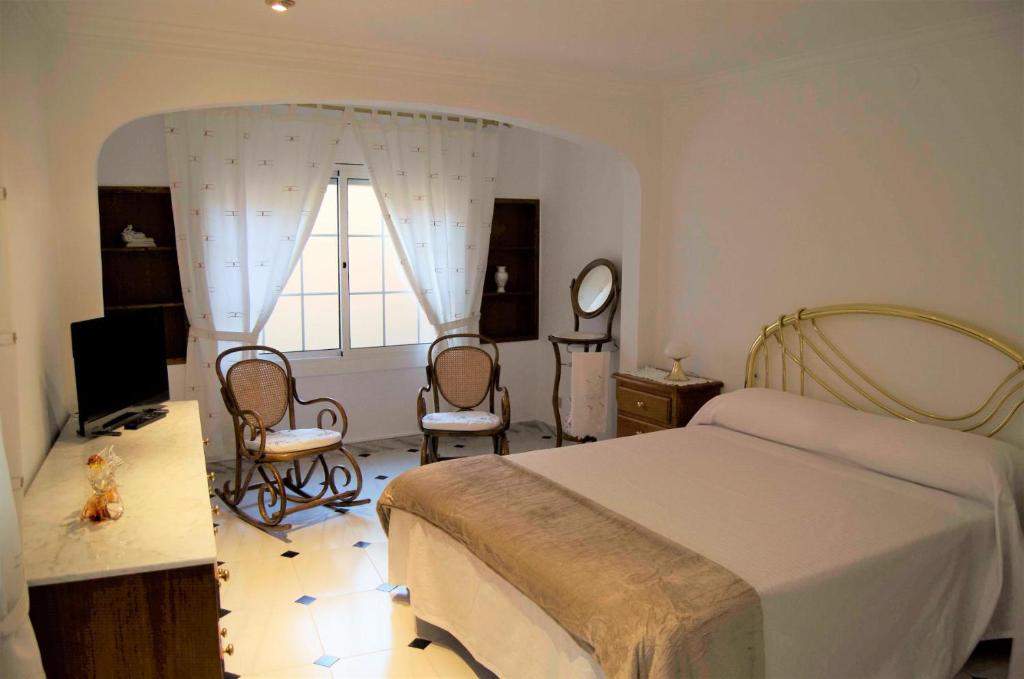 een slaapkamer met een bed en stoelen en een raam bij Casa Pintor in Sant Sadurní dʼAnoia