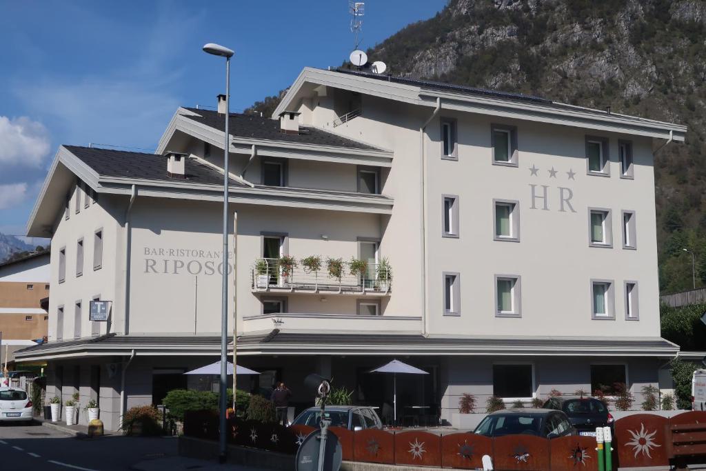 a large white building with cars parked in front of it at Hotel Riposo in San Pellegrino Terme