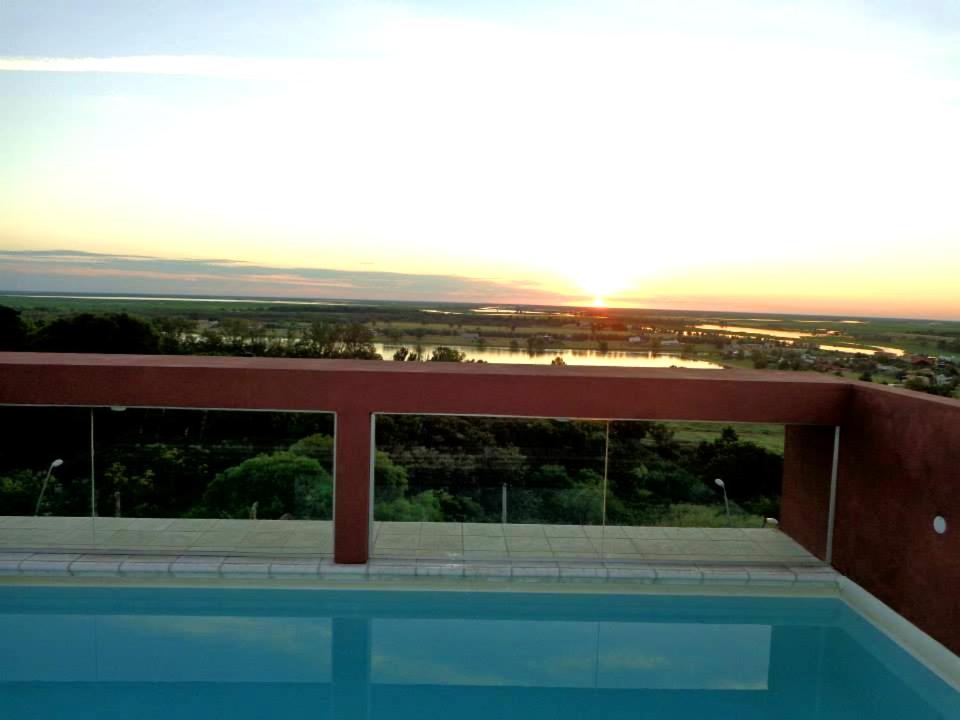 a building with a swimming pool and the sunset at Rio Manso Apartamentos in Victoria
