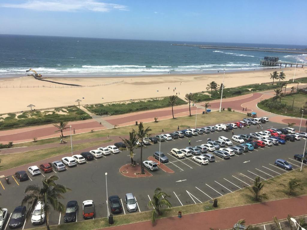 a parking lot with cars parked next to the beach at Tenbury Apartments in Durban