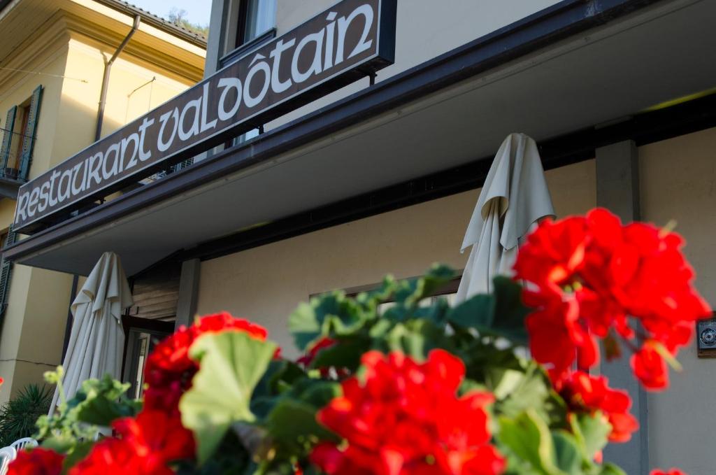 un panneau sur un bâtiment avec des fleurs rouges et des parasols dans l'établissement Hotel Valdotain, à Villeneuve