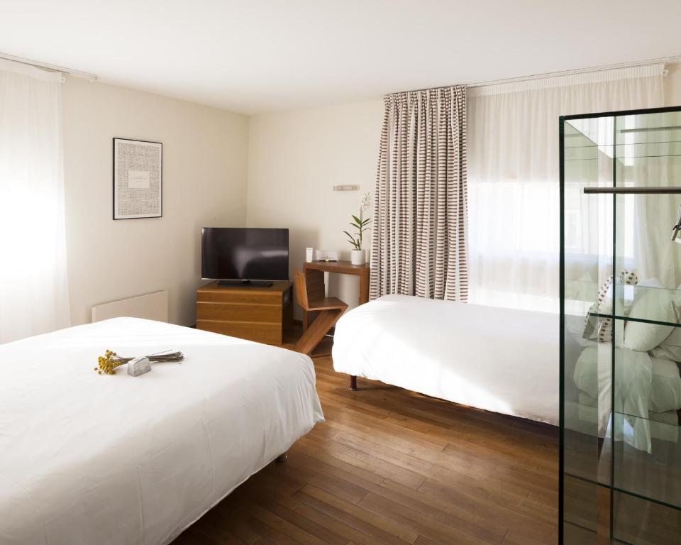 Cette chambre comprend deux lits et une télévision. dans l'établissement Hôtel La Pérouse, à Nantes