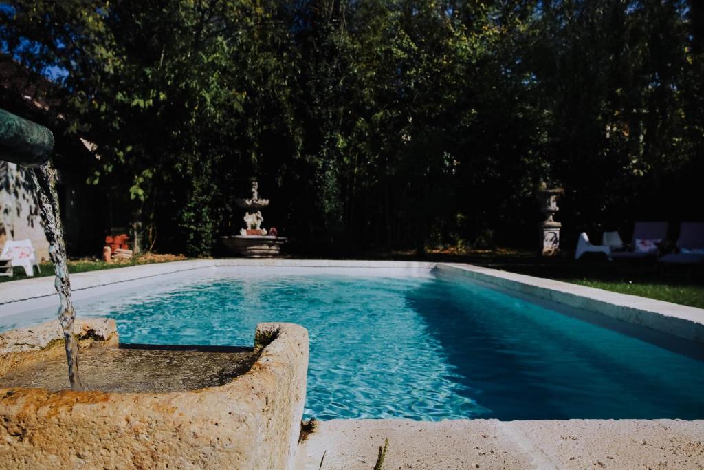 a swimming pool with a fountain in a yard at La Maison Bleue in Villeréal