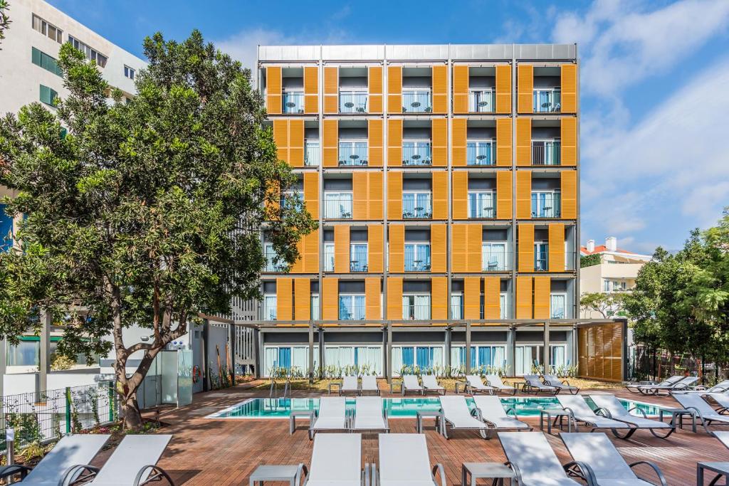 um hotel com piscina e espreguiçadeiras em frente a um edifício em Pestana Casino Studios no Funchal