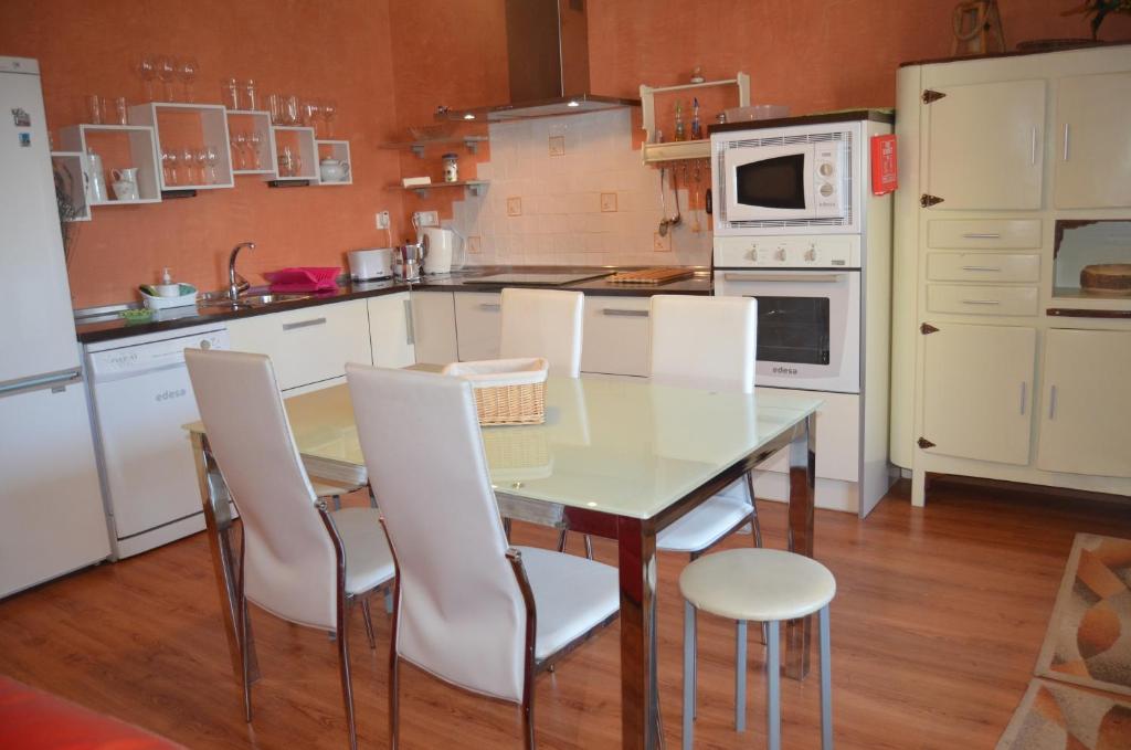eine Küche mit einem Glastisch und weißen Stühlen in der Unterkunft Casa Alfredo in Villamarciel