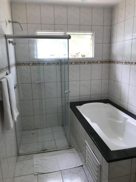 a bathroom with a shower and a tub and a sink at Pousada Vila Verde in Porto Belo