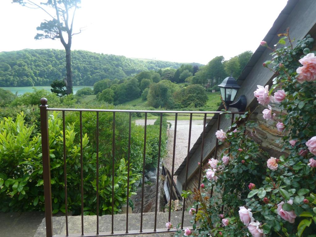 a balcony with a view of a river and flowers at Higher Greenway Annexe in Brixham