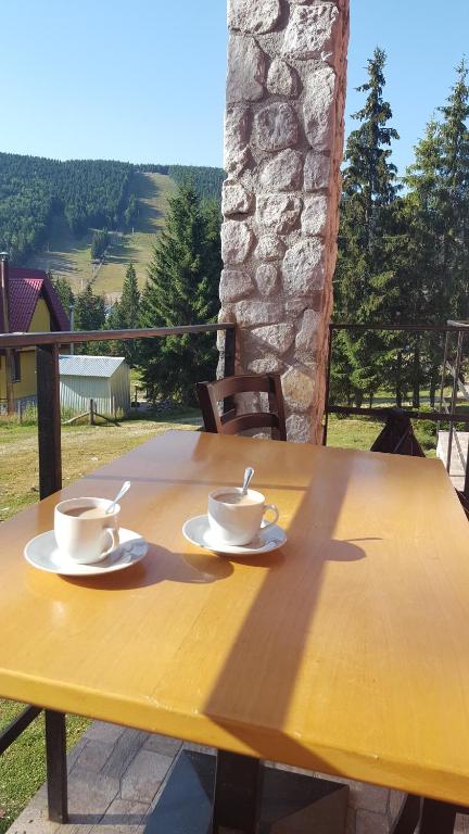 Una mesa amarilla con dos tazas encima. en Casa Bogdan, en Vartop