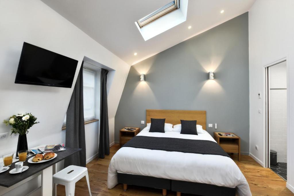 巴黎的住宿－蒙特貝洛公寓式酒店，卧室配有一张床,墙上配有电视。