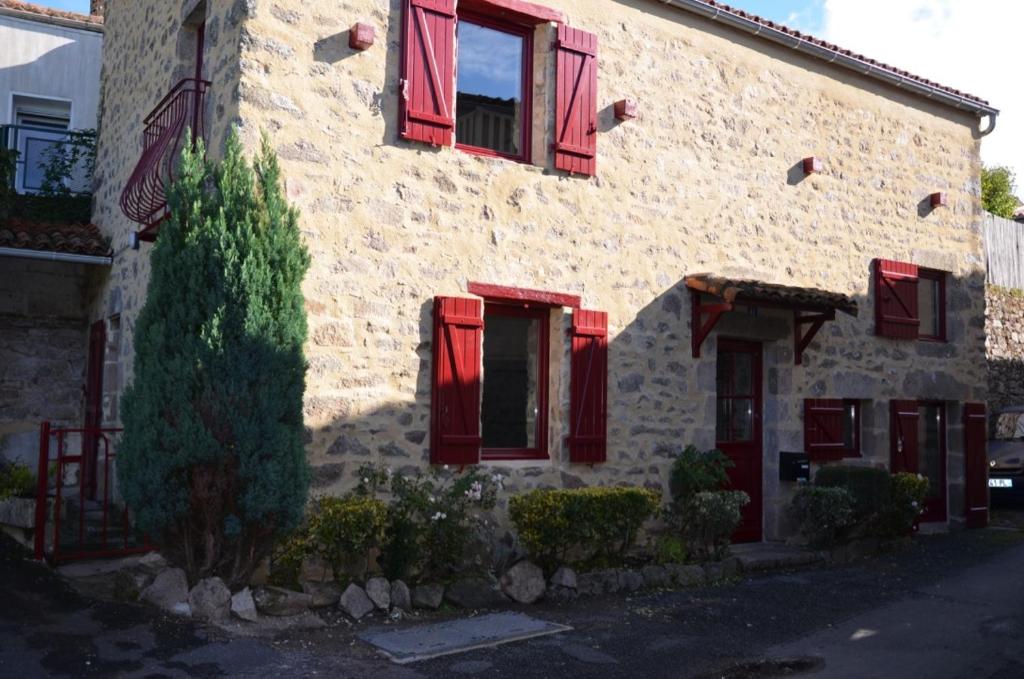 Mortagne-sur-SèvreにあるGîte "L'Ame d'Antan" 5 personnes proche puy du fouの赤い鎧戸と木が目の前にある建物