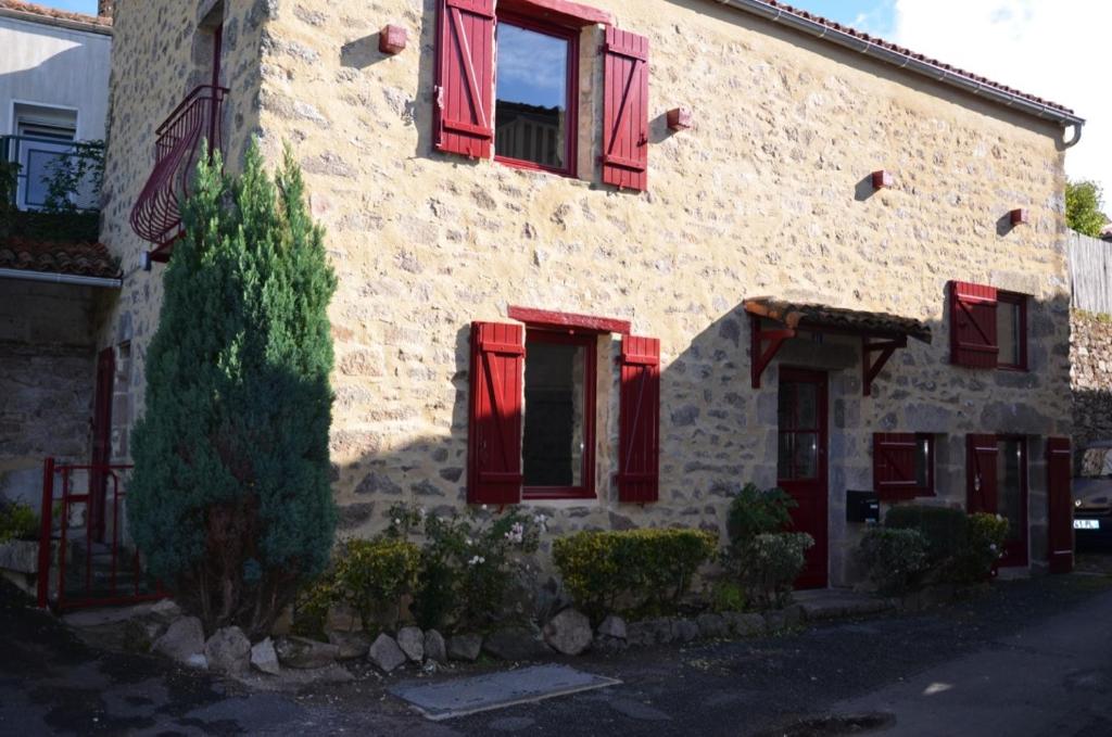 un bâtiment avec des volets rouges et un arbre devant lui dans l'établissement Gîte 