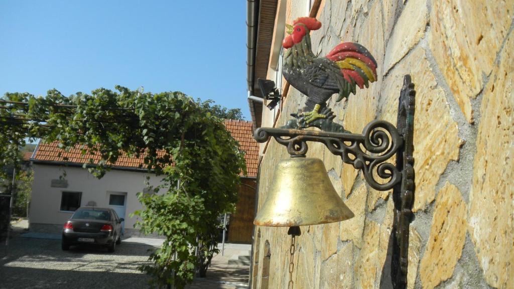 eine Glocke an der Seite eines Gebäudes mit einem Huhn darauf in der Unterkunft Casa Cezara in Silvaşu de Jos