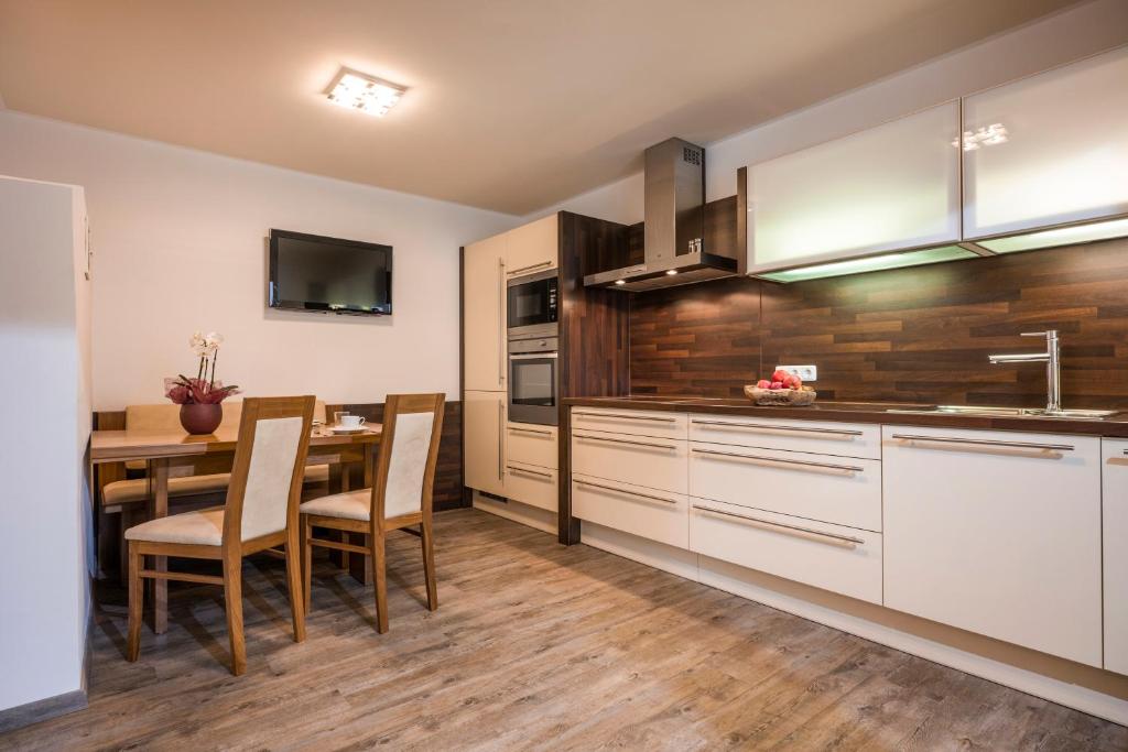 a kitchen with white cabinets and a table with chairs at Appartements Viteritti in Mayrhofen