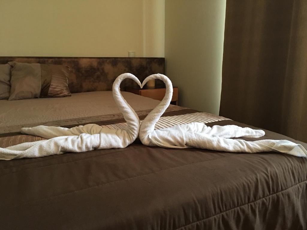 Dos cisnes blancos haciendo un corazón en una cama en Fiel Chef Alojamento Local, en Valongo