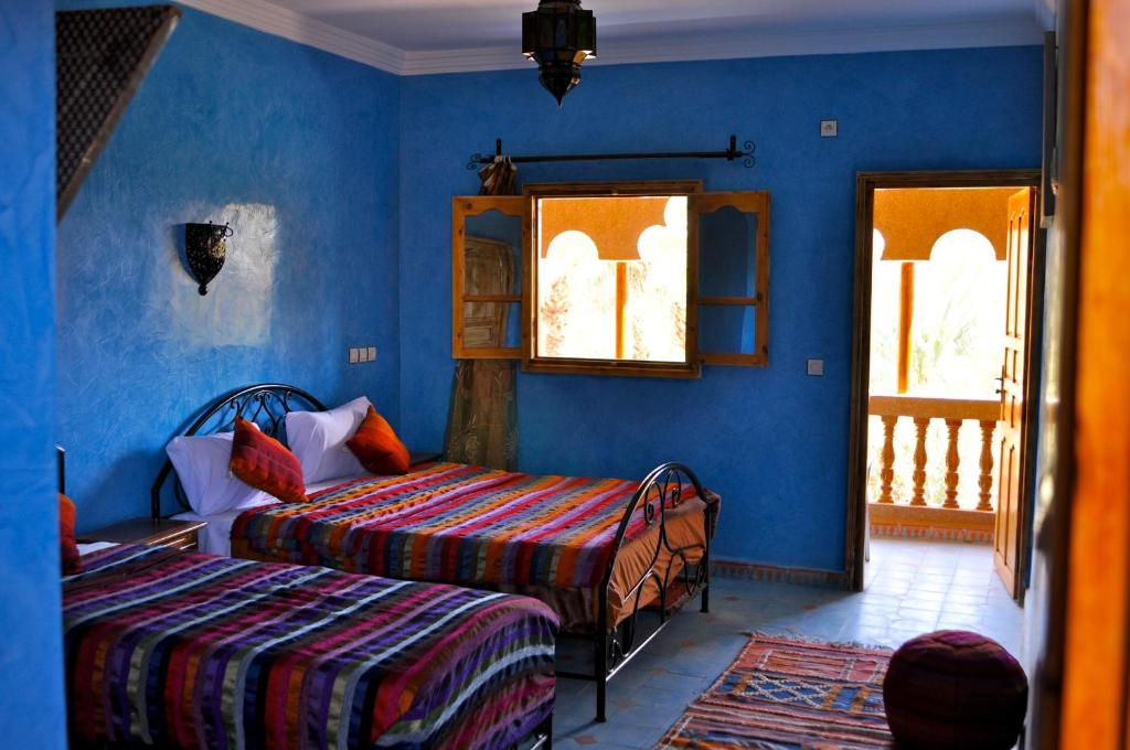 - une chambre avec 2 lits et des murs bleus dans l'établissement Chez Ali, à Zagora