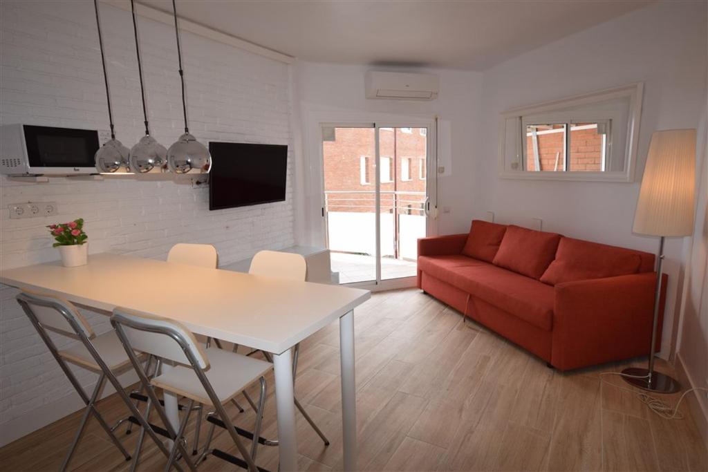 een woonkamer met een tafel en een rode bank bij Apartamento Playa Mar in Castelldefels