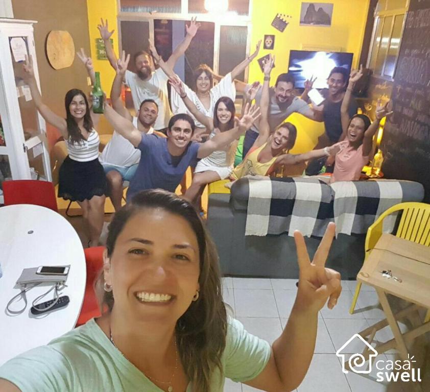 Un groupe de personnes posant une photo avec les mains levées dans l'établissement Casa Swell Hostel, à Fernando de Noronha