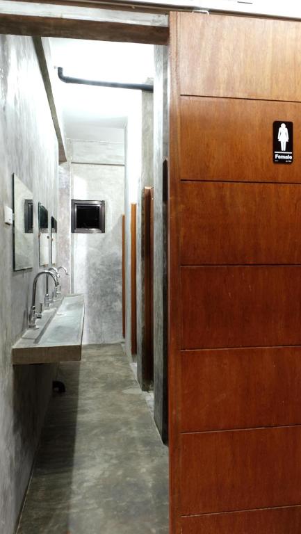 baño con puerta de madera y lavamanos en Dayon Hostel, en Corón