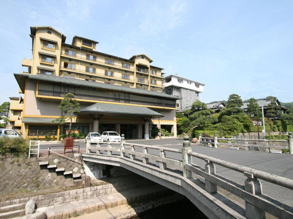 un pont sur une rivière avec un bâtiment dans l'établissement Hoseikan, à Matsue