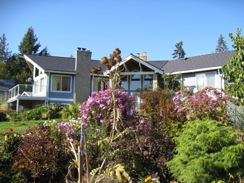 una casa con flores en el patio delantero en Cedar Acres Vacation Rental, en Fanny Bay