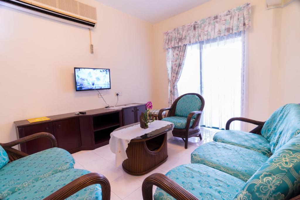 a living room with a couch and chairs and a tv at HIG Homestay Apartment in Kuah