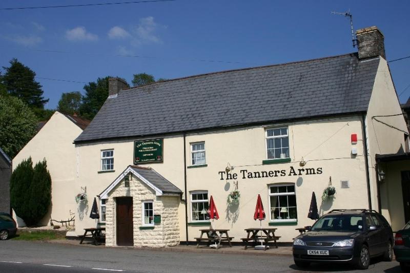 un bâtiment blanc avec deux tables devant lui dans l'établissement The Tanners Arms, à Devynock