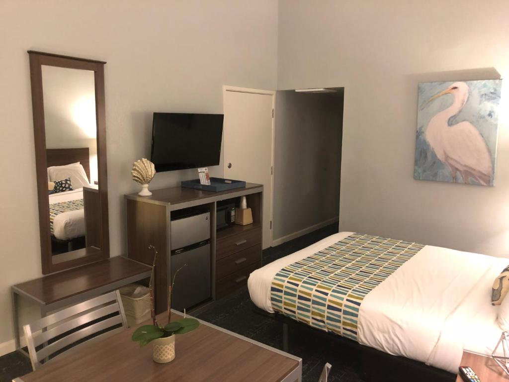 Pokój hotelowy z łóżkiem i lustrem w obiekcie Sand Dollar Inn w mieście Seaside