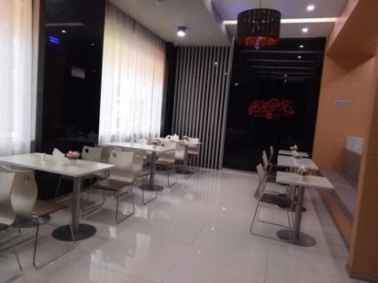 JUNYI Hotel Niongbo Xiangshan Bus Station في Xiangshan: مطعم فيه طاولات وكراسي في الغرفة