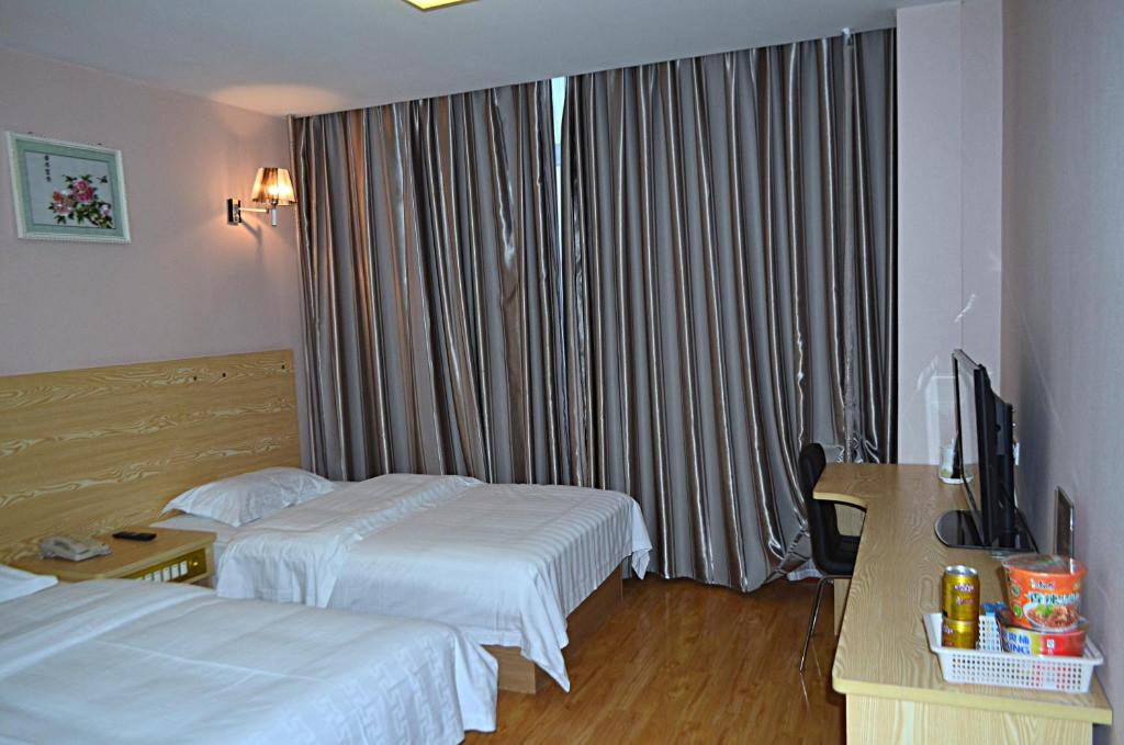 a hotel room with two beds and a television at JUNYI Hotel Shandong Qingdao Huangdao District Shiyou University in Xianlang