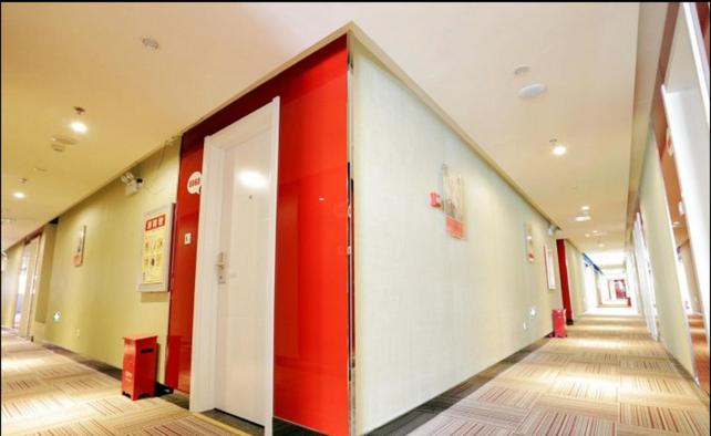 a hallway in a building with a red door at Thank Inn Chain Hotel Jiangsu Nanjing Gaochun Market in Gaochun