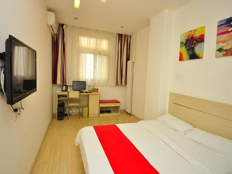 a bedroom with a bed and a desk and a television at Thank Inn Chain Hotel Shandong Dezhou Jiefang Road in Dezhou