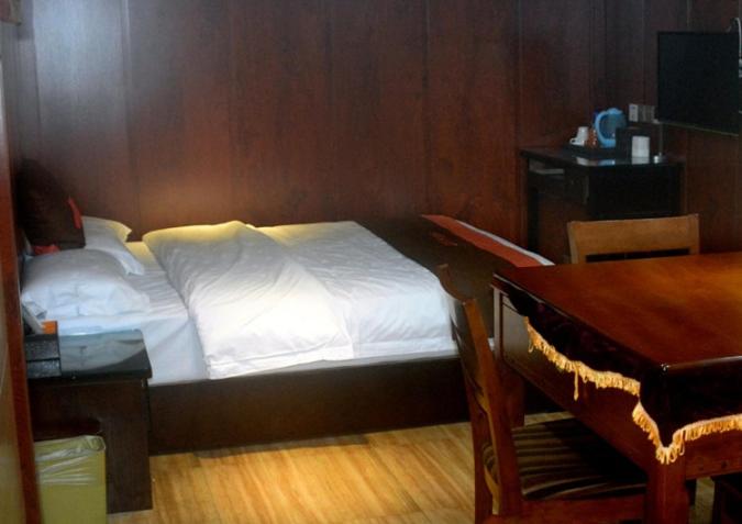 a bedroom with a bed and a desk and a table at JUNYI Hotel Guizhou Guiyang Bageyan Road in Guiyang