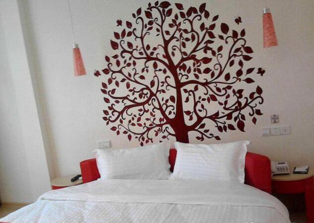 a tree stenciled on a wall above a bed at Thank Inn Chain Hotel Shandong Dezhou South City in Dezhou