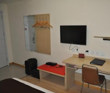a room with a desk with a monitor on a wall at Thank Inn Chain Hotel Shandong Tengzhou Train Station Wentian Squre in Tengzhou