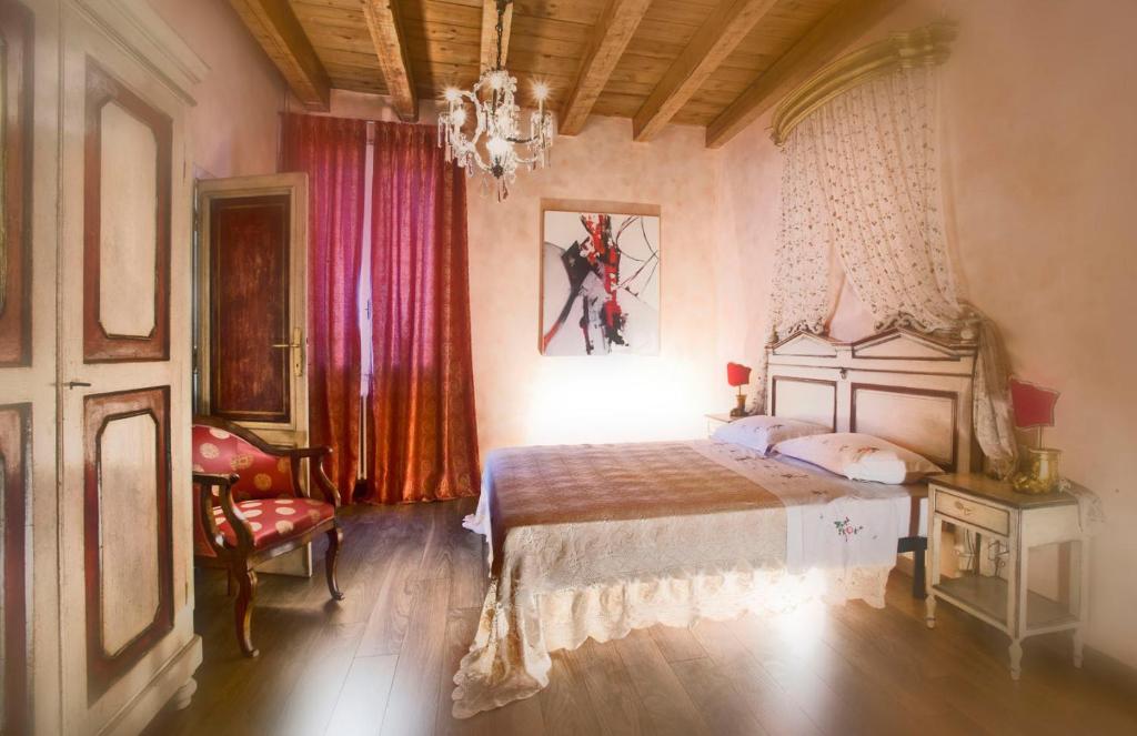 a bedroom with a bed and a chandelier at Antica Dimora Conti Custoza in Roverbella