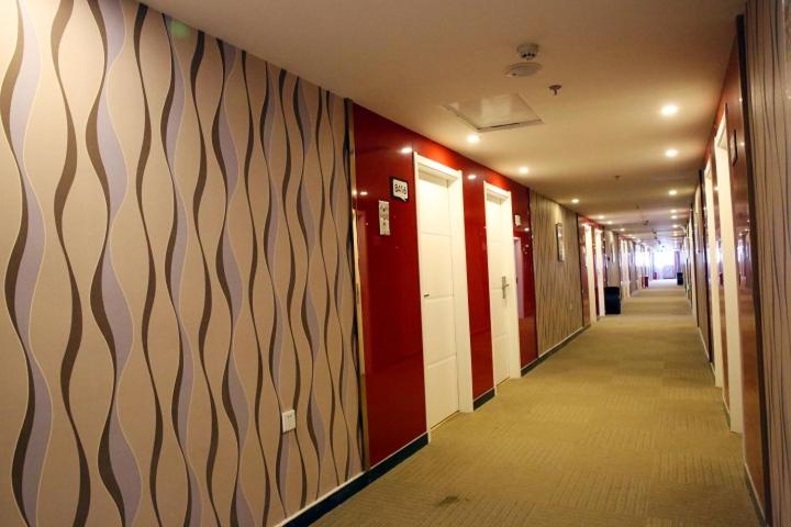 um corredor com paredes vermelhas e brancas num corredor com um desvio lateral em Thank Inn Chain Hotel Hebei Handan Guantao Zhuxian Road em Nanxinzhuang