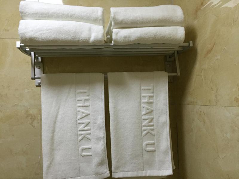 a pile of towels on a rack in a bathroom at JUNYI Hotel Shandong Zaozhuang Shanting District Xinyuan Road in Zaozhuang